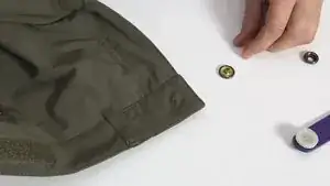 Übertritt: An der Position des alten Knopfloches den neuen Druckknopf anlegen und ggf. mit Kunststoffhalter fixieren. Mit einigen kräftigen Hammerschlägen die beiden Teile fest vernieten.